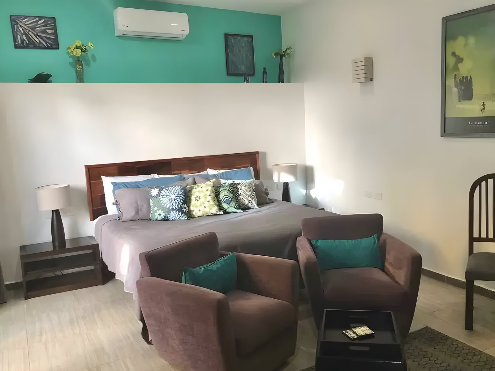 A king suite with a lounge corner and teal accent wall